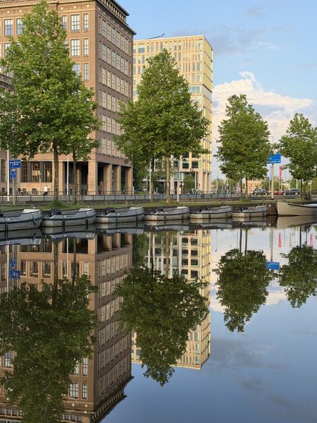 This photo captures a tranquil scene along Mauritskade in Oost, Amsterdam, where several small boats are neatly docked along a canal